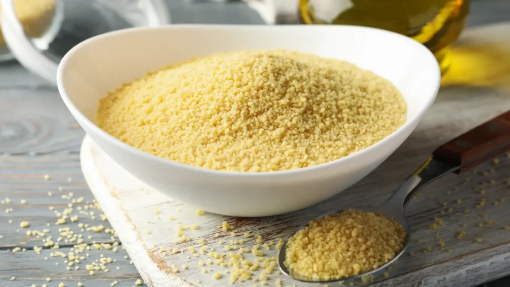 Cuisson Semoule de couscous fine dans un bol blanc, avec une cuillère et un flacon d'huile d'olive